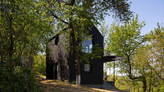 Minimalism în negru și materiale naturale într-o casă de vacanță, în context rural